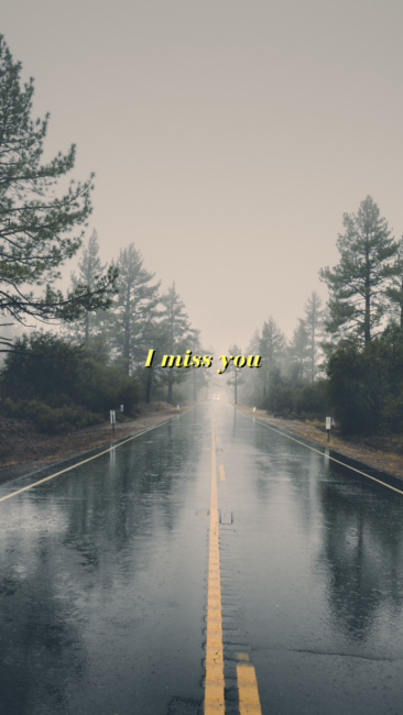 Empty road in the rain with the words 'I miss you'.